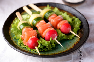 Appetizer on wooden skewers from lightly salted salmon, boiled potatoes, cucumber and radish.