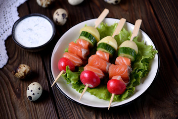 Appetizer on wooden skewers from lightly salted salmon, boiled potatoes, cucumber and radish.