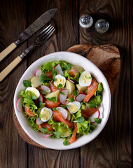 Salad from slightly salted salmon, boiled potatoes, quail eggs with cucumber and radish.