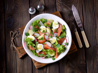 Salad from slightly salted salmon, boiled potatoes, quail eggs with cucumber and radish.