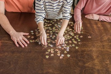 Close-up partial view of family with one child playing with puzzles on table