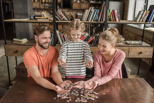 Happy Family With One Child Playing With Puzzles At Home