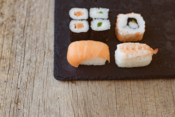 Sushi Set sashimi and sushi rolls served on stone slate