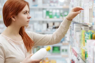 Foto op Canvas So many brands. Shot of an attractive young female concentrated on choosing medicine on the pharmacy shelf. © Nestor