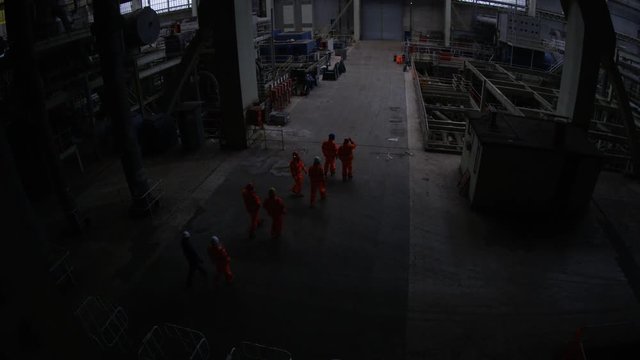 Team of workers at fuel plant come up from underground & walk into daylight