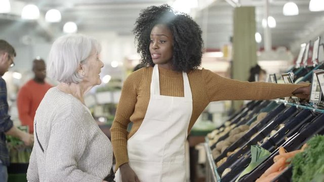  Friendly worker in a supermarket assisting senior lady buying groceries