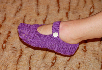 A woman's leg in a lilac woolen slipper