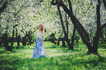 Fototapeta na wymiar beautiful young woman in floral maxi skirt walking in spring
