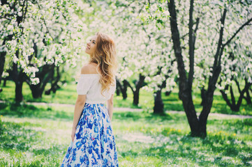 Naklejka na ściany i meble beautiful young woman in floral maxi skirt walking in spring