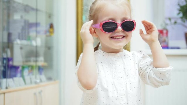 Little Girl tries medical fashion glasses and laughing at camera
