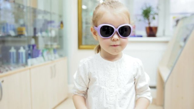 Little Girl tries medical blue glasses - shopping in clinic