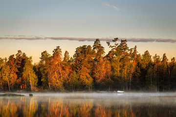 Early morning sunrise by lake with mist and boat
