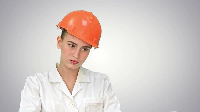 Stressed female engineer in helmet checking constraction plan on white background.