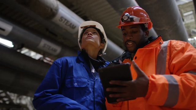 Male and female engineers in power station looking at computer tablet