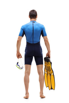 Man in wetsuit holding a diving mask and swimming fins