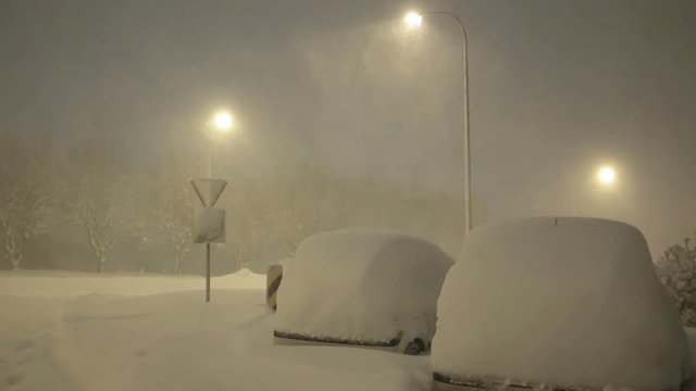 Cars under street lamps covered in deep snow winter blizzard Reykjavik Iceland