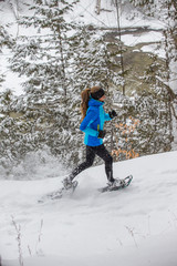 Lone woman running in the forest on snowshoes