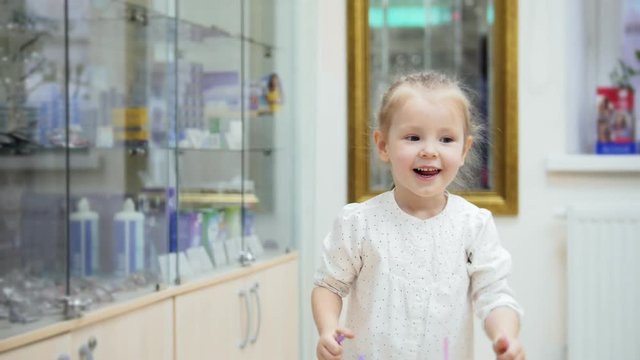 Adorable blonde Girl dancing and asks mommy to buy pink glasses in medical store - shopping in clinic