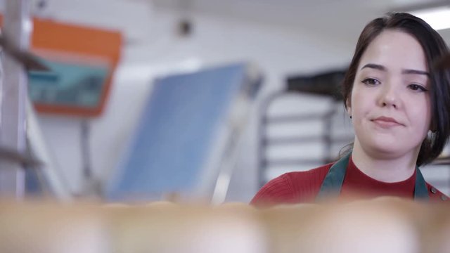  Worker in bakery kitchen counting bread batch & loading trays onto rack