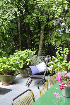 Flowery and wooded terrace with chaise longue and blue cushion for a moment of relaxation