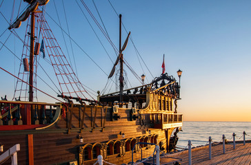 A stern of a touristic pirate ship at the pier (molo) in Sopot, Poland, in sunrise light - obrazy, fototapety, plakaty