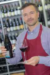 wine merchant showing bottle and glass of wine