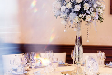 luxury wedding decor with flowers and glass vases and number  of setting on round tables. arrangements of decorations with stones jewels at wedding reception. expensive catering. space for text