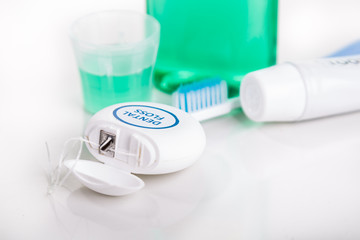 Dental floss focused with  toothbrush, toothpaste, mouthwash, at background