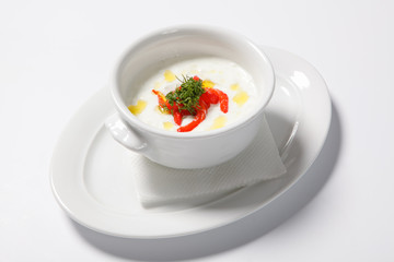 Cream soup in white cup on white table background