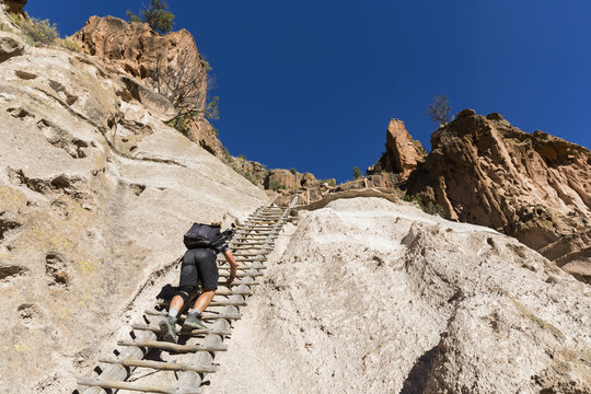 USA, New Mexico, Frijoles Canyon, Bandelier National Monument, Ruins and reconstructed kiva of the Ancestral Pueblo People, tourist on ladder towards Alcove House