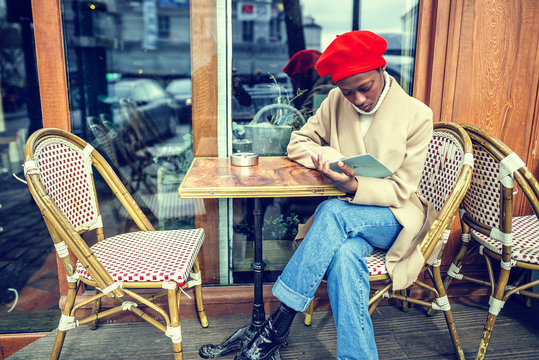 Young woman in Paris reading menu in a cafe