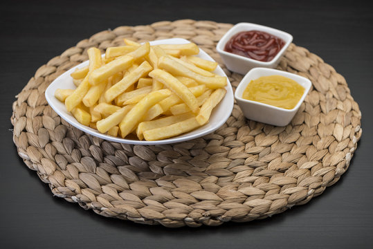 French fries on wooden chopping board with catchup and mustard sauce  