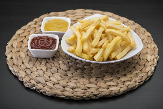 French fries on wooden chopping board with catchup and mustard sauce  