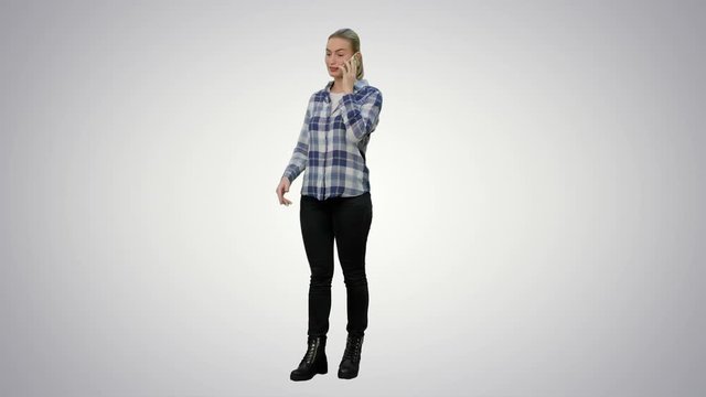 Young woman in casual talking gossips via cellphone on white background.