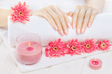 Obraz na płótnie Canvas beautiful pink manicure with chrysanthemum and towel on the white wooden table. spa