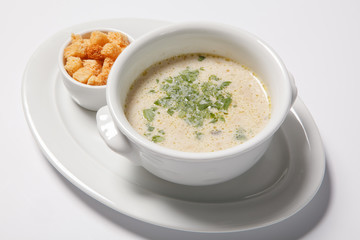 delicious creamy soup with croutons and greens on white dish