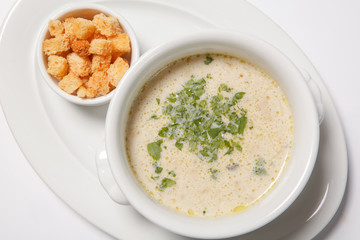 delicious creamy soup with croutons and greens on white dish