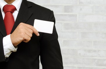 businessman showing business card on brick wall background, selective focus, copy space, color tone effect.