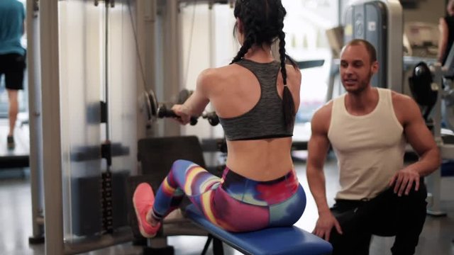 Instructor helping woman on rowing machine 