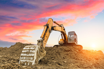 excavator in construction site on sunset sky background - obrazy, fototapety, plakaty