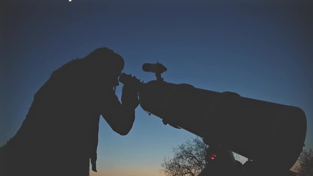 Girl looking at the sky through a telescope.