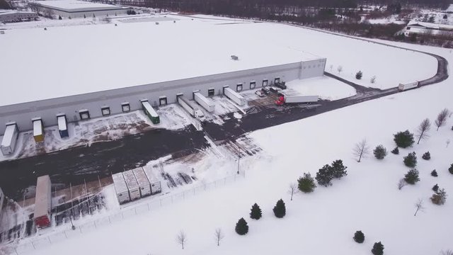 Aerial warehouse parking lot covered in snow