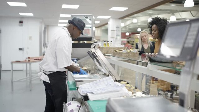 Happy worker on supermarket cheese counter serving customers &amp; dancing