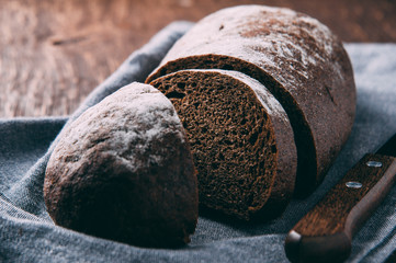 Rye bread and knife on dark background