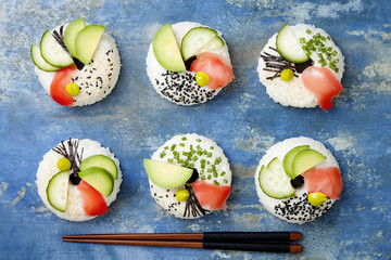 Vegan sushi donuts set with pickled ginger, avocado, cucumber, chives, nori and sesame on blue background. Sushi-food hybrids trend. Overhead, top view, flat lay.