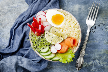 Veggies detox Buddha bowl recipe with egg, carrots, sprouts, couscous, cucumber, radishes and seeds. Top view, flat lay, copy space