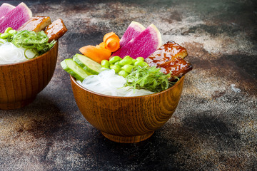 Vegan tofu poke bowls with seaweed, watermelon radish, cucumber, edamame beans and rice noodles. Copy space background