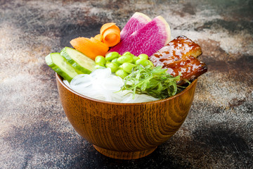 Vegan tofu poke bowls with seaweed, watermelon radish, cucumber, edamame beans and rice noodles. Copy space background
