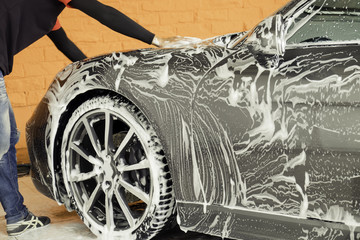 Man washing a black car with a cloth