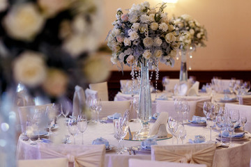 luxury decorated tables at rich wedding reception. stylish arrangements of flowers and jewels on table in glass vase, dish and glasses on tablecloth. expensive catering. space for text